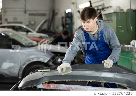 Young man auto mechanic handle polishes body parts Young man auto mechanic handle polishes body parts 132764229