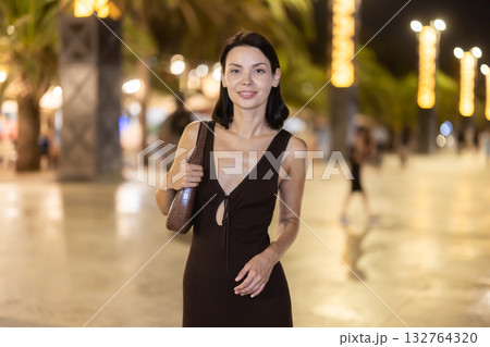 Woman walking along coastal promenade at night in Barcelona Woman walking along coastal promenade at night in Barcelona 132764320