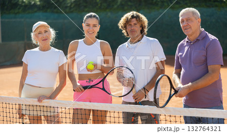 Group of friends or family in sportswear spending time playing sports and posing on tennis courts after match 132764321