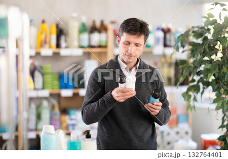 Middle-aged man choosing some deodorant at department store Middle-aged man choosing some deodorant at department store 132764401