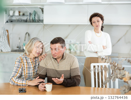 Family members quarreling in the kitchen and old woman trying to calm angry man 132764436