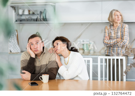 Family members quarreling in the kitchen and middle-aged woman trying to calm angry man 132764472