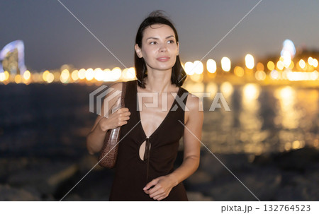Young woman standing at seaside against background of twin towers Young woman standing at seaside against background of twin towers 132764523