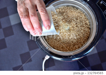 家庭用精米機に玄米を入れる 132764565