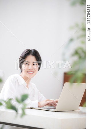 観葉植物の緑がある部屋でパソコンをする女性の主婦やデザイナーのリモートワークや在宅などのイメージ 132764811