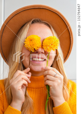 Woman faceless yellow sweater closing eyes with orange dahlia into camera Autumn Fall Bouquet for Thanksgiving holiday. Seasonal Warm colorful blossom flowers arrangement festive decoration 132764847