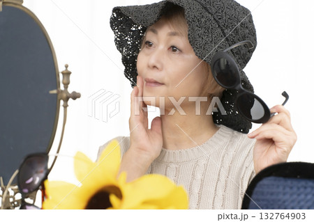 夏の外出で紫外線対策に帽子.サングラスを選ぶシニア女性 夏の外出で紫外線対策に帽子.サングラスを選ぶシニア女性 132764903