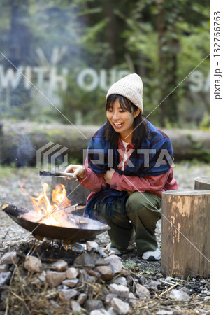 キャンプ場で焚き火をする女性 132766763