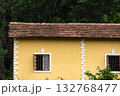 Old small Portuguese style yellow house surrounded by green trees. 132768477