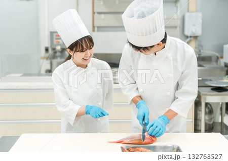 魚を調理するコックコート姿の男女スタッフ(調理師・料理人・生鮮市場・食品加工) 魚を調理するコックコート姿の男女スタッフ(調理師・料理人・生鮮市場・食品加工) 132768527