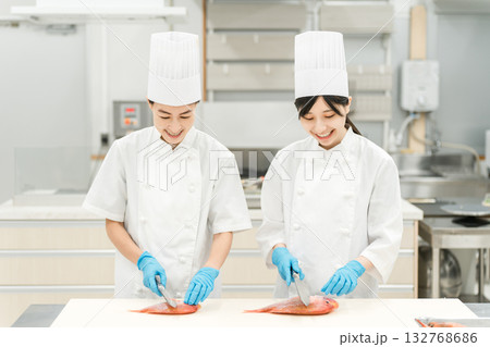 魚を調理するコックコート姿の女性スタッフ（調理師・専門学校・料理人・生鮮市場・食品加工） 132768686