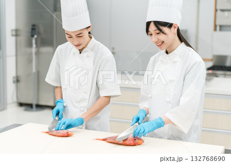 魚を調理するコックコート姿の女性スタッフ(調理師・専門学校・料理人・生鮮市場・食品加工) 魚を調理するコックコート姿の女性スタッフ(調理師・専門学校・料理人・生鮮市場・食品加工) 132768690