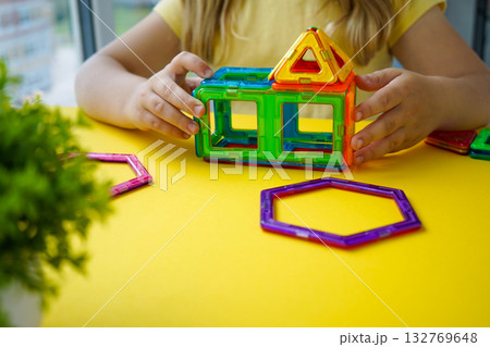 A young mind explores geometry through play, connecting colorful magnetic shapes to create balanced three-dimensional constructions. A young mind explores geometry through play, connecting colorful magnetic shapes to create balanced three-dimensional constructions. 132769648