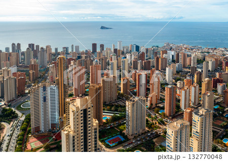 Panoramic view of Benidorm with numerous skyscrapers facing the Mediterranean coast. Beautiful contrast of city and sea under sunny skies.  132770048