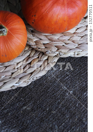 Two orange pumpkins lying on placemats. On a rough linen burlap background. Close-up. 132770511