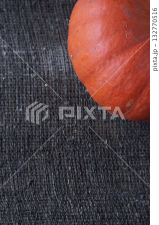 Orange pumpkin fragment. On a rough linen burlap background. Shot from above. 132770516