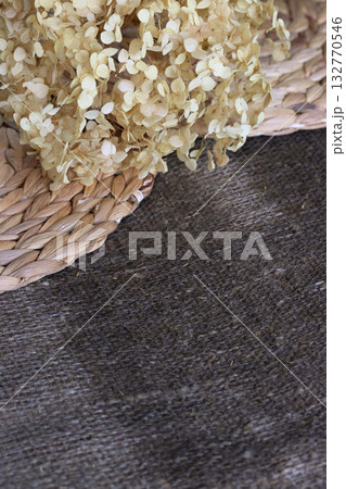 Lush dried hydrangea flower on damp linen burlap and water hyacinth placemats, Autumn background. Lush dried hydrangea flower on damp linen burlap and water hyacinth placemats, Autumn background. 132770546