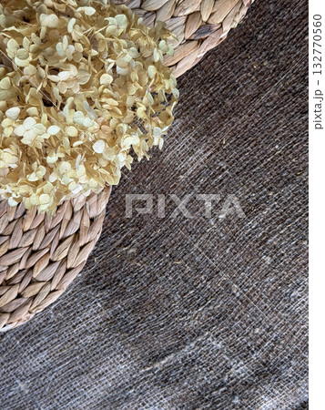 Lush dried hydrangea flower on damp linen burlap and water hyacinth placemats, Autumn background, shot from above Lush dried hydrangea flower on damp linen burlap and water hyacinth placemats, Autumn background, shot from above 132770560