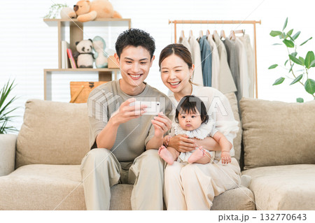 自宅のソファーでスマホを見ながら談笑する家族,ファミリー 自宅のソファーでスマホを見ながら談笑する家族,ファミリー 132770643