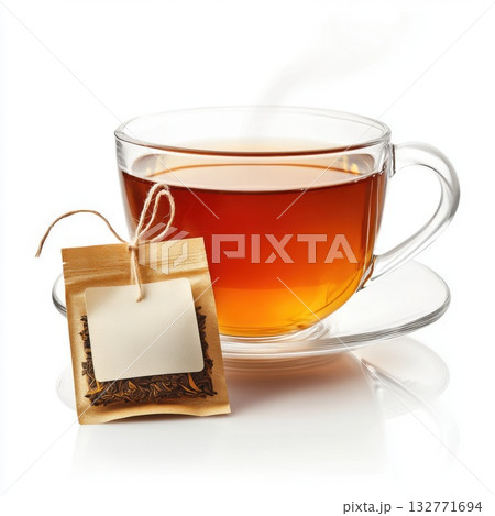 Warm tea in a glass cup beside a tea bag on a saucer, perfect for a cozy afternoon break 132771694