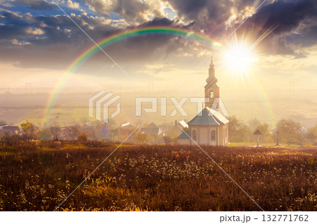 old church in the village in autumn at sunset. view of countryside landscape from a hill in hazy evening light. empty rural fields. pilgrimage storytelling image under the rainbow old church in the village in autumn at sunset. view of countryside landscape from a hill in hazy evening light. empty rural fields. pilgrimage storytelling image under the rainbow 132771762