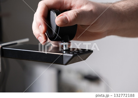 Person's hand meticulously attaching a robust black furniture caster wheel with a metal threaded screw, for equipment mobility or easy assembly 132772188