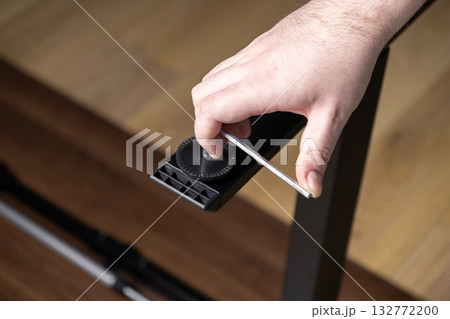 Skilled hand precisely using an Allen wrench to securely fasten a black furniture leg, illustrating efficient home assembly, DIY projects, and practical maintenance solutions 132772200