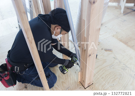 制震ダンパーを取り付ける大工さん 132772821