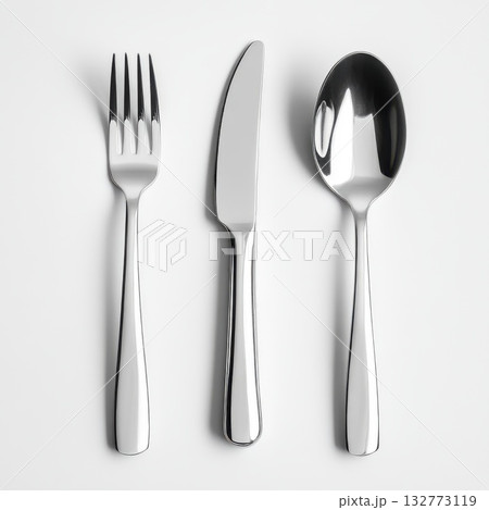Silver cutlery set featuring a fork, knife, and spoon arranged neatly on a clean white background 132773119