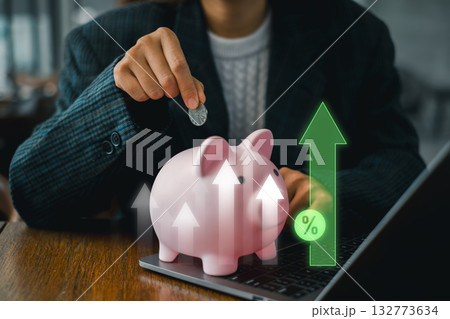 A person placing a coin into a piggy bank with upward arrows symbolizing profit growth and financial success. A person placing a coin into a piggy bank with upward arrows symbolizing profit growth and financial success. 132773634