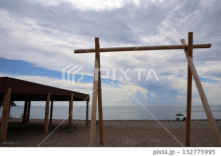 Beach landscape with wooden structure, sea view, cloudy sky, and coastal scene, perfect for travel, vacation, or outdoor adventure concepts, peaceful beach scenery 132775995