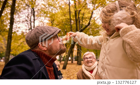 Daughter feeding father slice of pizza while grandmother watching and smiling 132776127