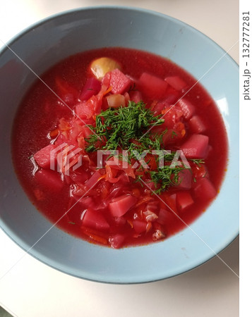 Traditional borscht soup with beetroot, potatoes and fresh dill served in a blue bowl. Concept of Eastern European cuisine and homemade comfort food Traditional borscht soup with beetroot, potatoes and fresh dill served in a blue bowl. Concept of Eastern European cuisine and homemade comfort food 132777281