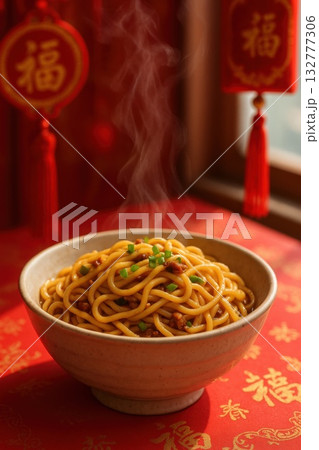 Hot bowl of traditional Chinese noodles garnished with green onions on a festive red tablecloth. Concept of Lunar New Year food symbolism and cultural heritage 132777306