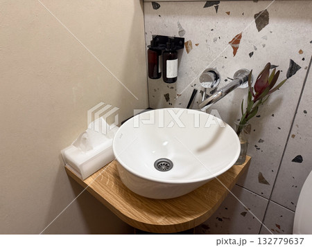 Modern bathroom sink with soap dispensers and tissue box. Cleanliness, harmony and balance in minimalist interior design. 132779637