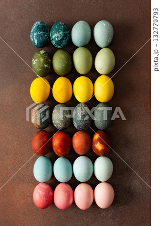 Brightly colored Easter eggs are arranged in a grid, displaying shades like pink, blue, green, and yellow. These eggs symbolize renewal and are often part of festive gatherings 132779793