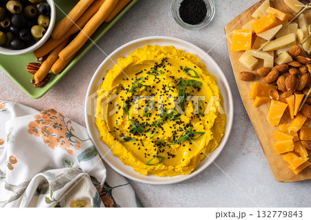 Gather around a colorful charcuterie board featuring turmeric hummus, cheese, nuts, and olives. This delightful spread invites friends to share tasty bites and enjoy each other company Gather around a colorful charcuterie board featuring turmeric hummus, cheese, nuts, and olives. This delightful spread invites friends to share tasty bites and enjoy each other company 132779843