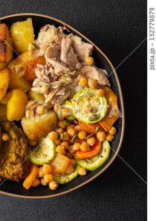 This hearty breakfast showcases a plate filled with baked sweet potatoes, carrots, zucchini, lentil cutlets, chicken breast 132779879
