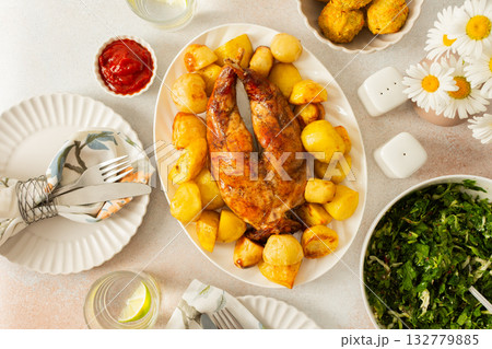 A hearty meal features a beautifully baked rabbit surrounded by golden potatoes, Accompanying the dish is a fresh salad, soft chickpea buns. This inviting setup showcases a warm dining A hearty meal features a beautifully baked rabbit surrounded by golden potatoes, Accompanying the dish is a fresh salad, soft chickpea buns. This inviting setup showcases a warm dining 132779885