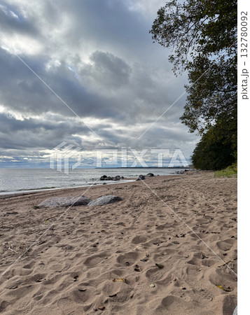 Sandy beach with scattered rocks along calm sea and cloudy autumn sky. Sandy beach with scattered rocks along calm sea and cloudy autumn sky. 132780092
