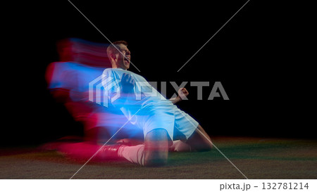 Soccer player celebrating goal on knees with red and blue motion streaks 132781214