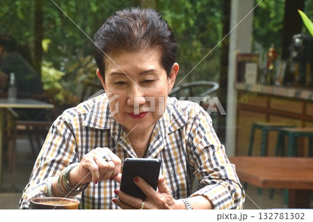 elder woman enjoy to drinking coffee read book and used mobile phone in cafe garden elder woman enjoy to drinking coffee read book and used mobile phone in cafe garden 132781302