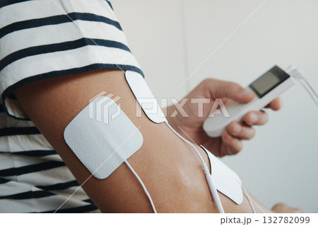 a man using a muscle stimulator on his arm a man using a muscle stimulator on his arm 132782099
