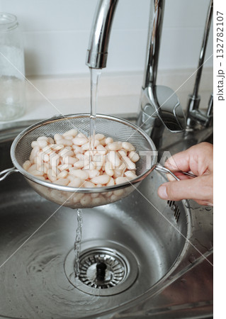 rinsing white beans in the kitchen sink rinsing white beans in the kitchen sink 132782107