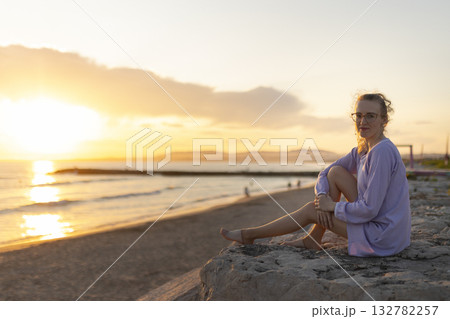 Young woman enjoying tranquil golden hour on beach at sunset Young woman enjoying tranquil golden hour on beach at sunset 132782257