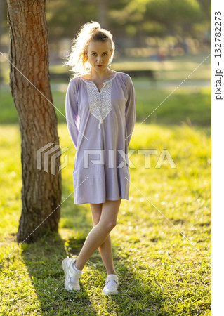 Young woman standing in park enjoying golden hour sunlight Young woman standing in park enjoying golden hour sunlight 132782273