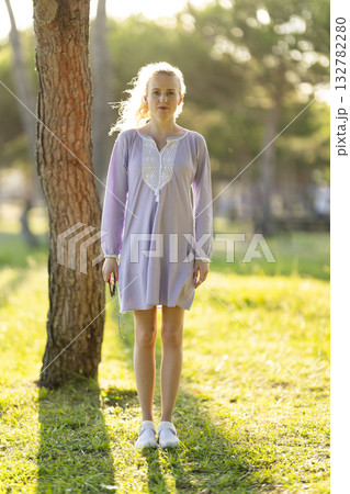 Young woman standing relaxed in nature during golden hour Young woman standing relaxed in nature during golden hour 132782280