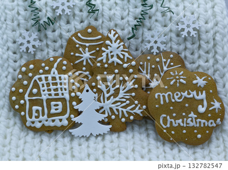 Gingerbread cookies decorated with royal icing on white knitted background, holidays greeting card 132782547