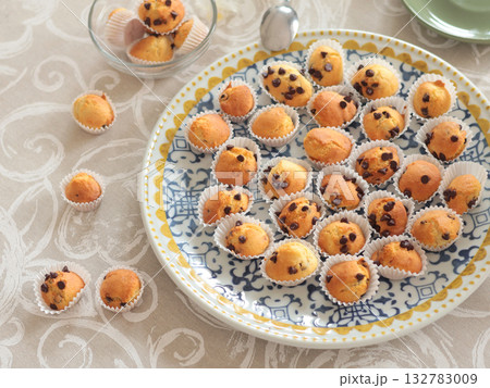 Mini chocolate cupcakes on patterned ceramic plate. Holidays and lifestyle. Food on table covered with tablecloth. Mini chocolate cupcakes on patterned ceramic plate. Holidays and lifestyle. Food on table covered with tablecloth. 132783009