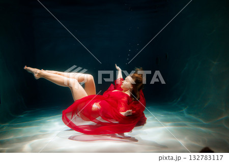 Balletinspired female figure with flowing red tulle beneath water 132783117